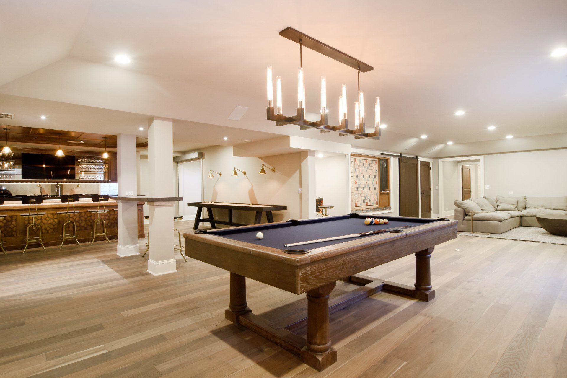A pool table in a basement with a chandelier hanging from the ceiling