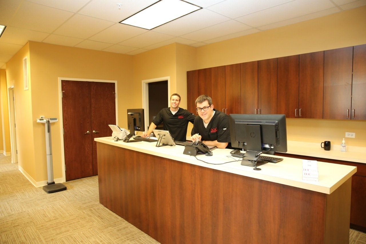 Two men are sitting at a desk in an office.