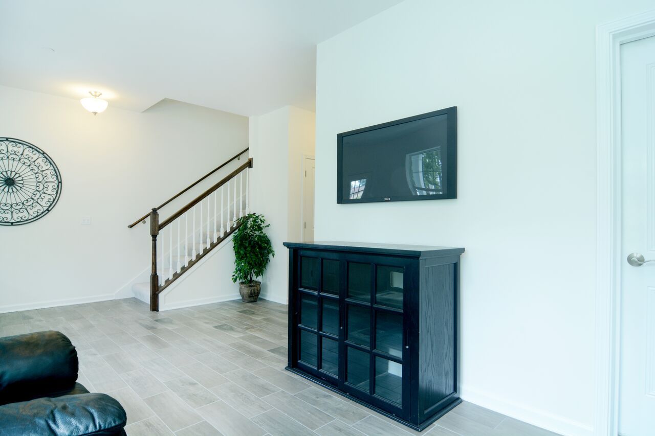 A living room with a black dresser and a flat screen tv on the wall.