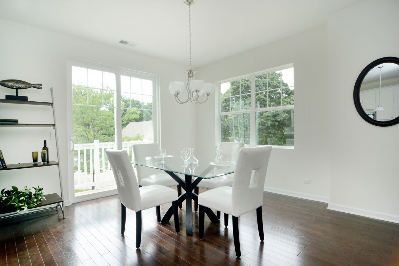 A dining room with a glass table and white chairs