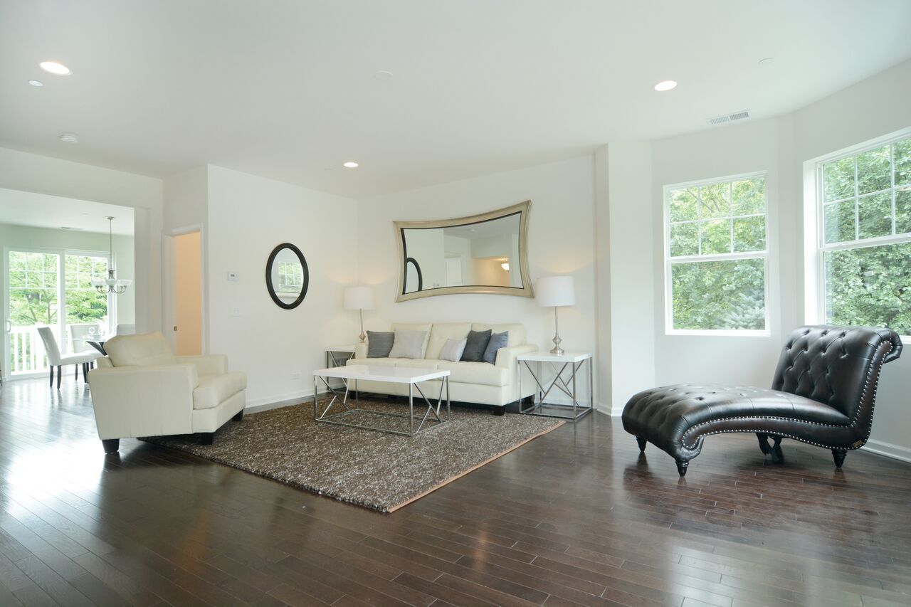 A living room with a couch , chairs , and a large mirror on the wall.