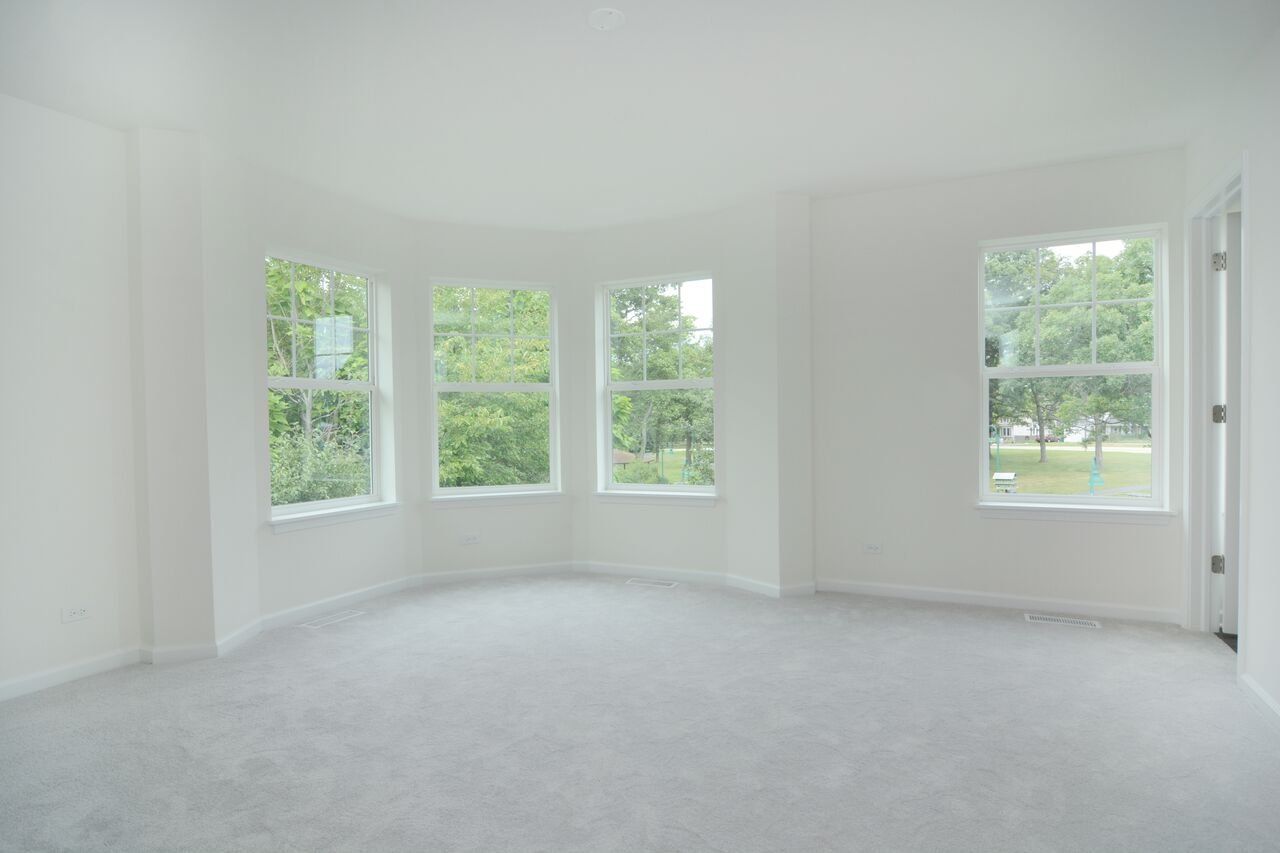 An empty room with a lot of windows and a carpet.