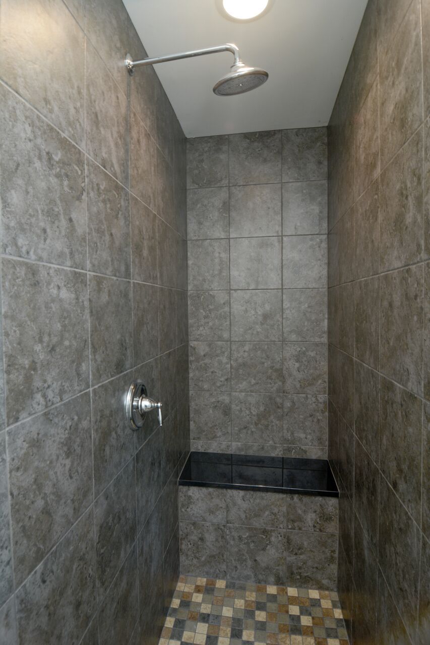 A shower with a shower head hanging from the ceiling.