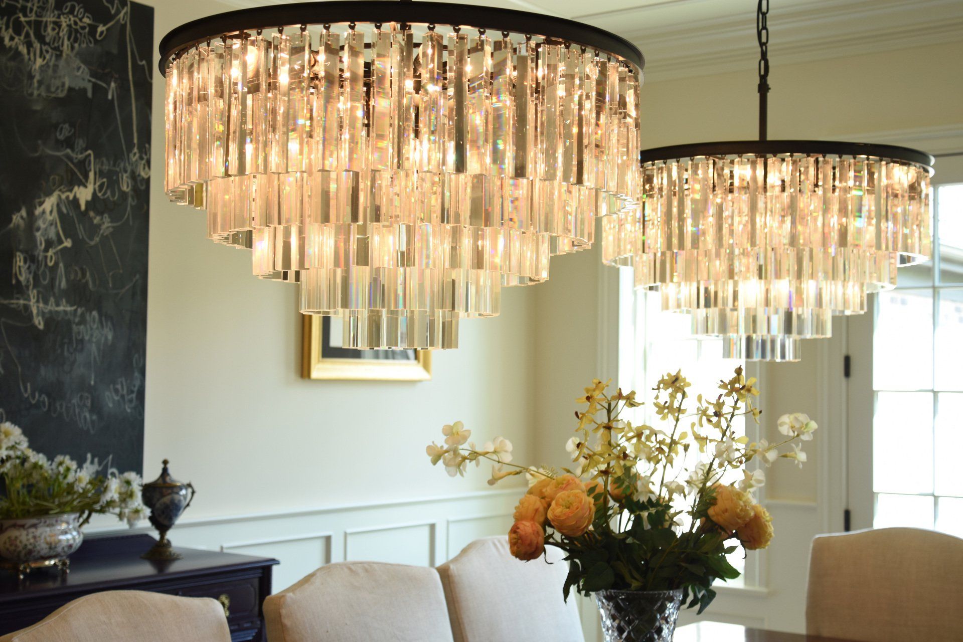 A dining room with two chandeliers and a vase of flowers