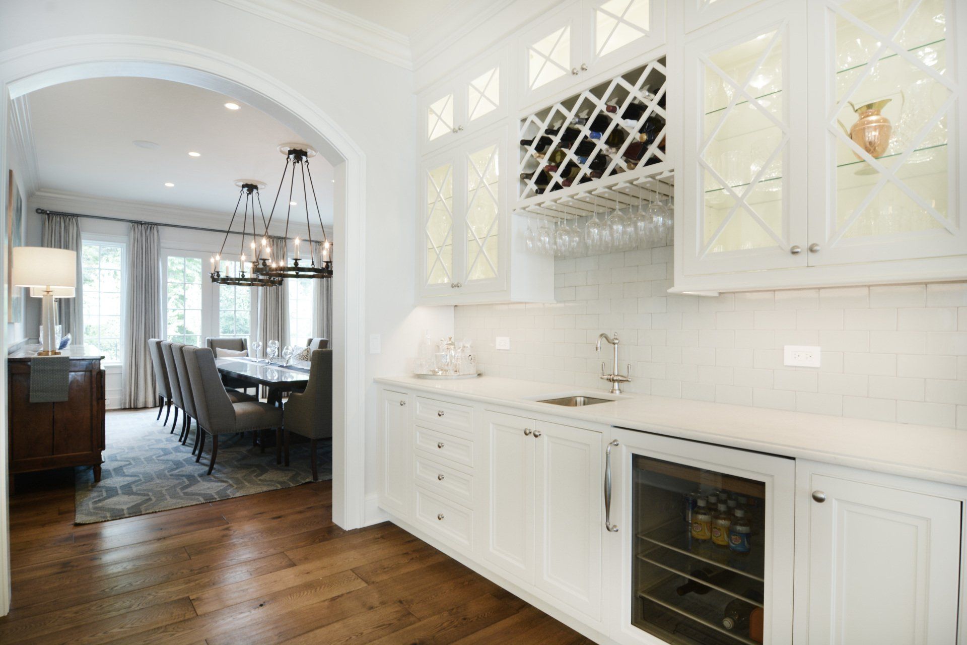A kitchen with white cabinets , a wine cooler and a wine rack.