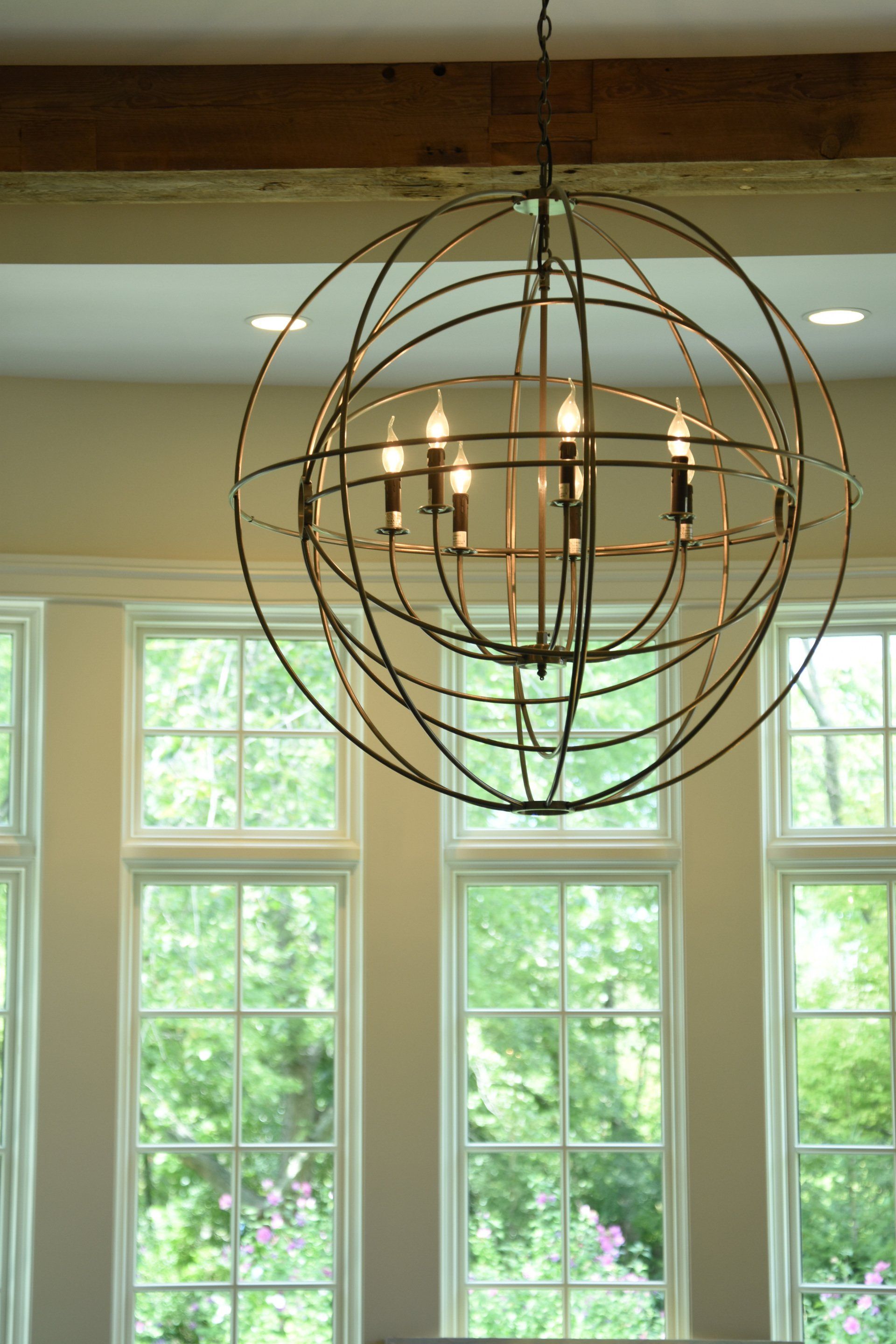 A large chandelier is hanging from the ceiling in a room with lots of windows