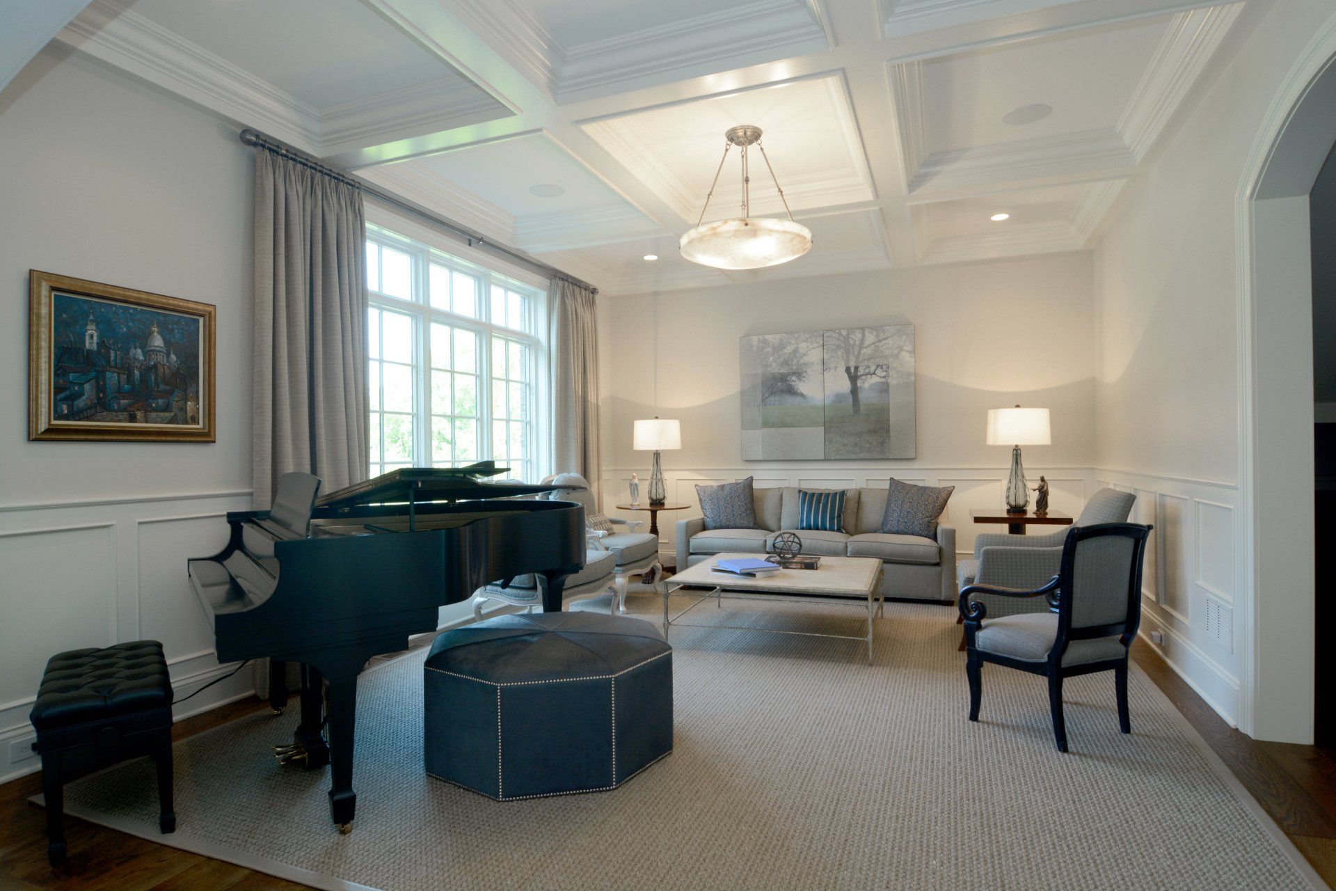 A living room with a piano , couch , chairs and ottoman.