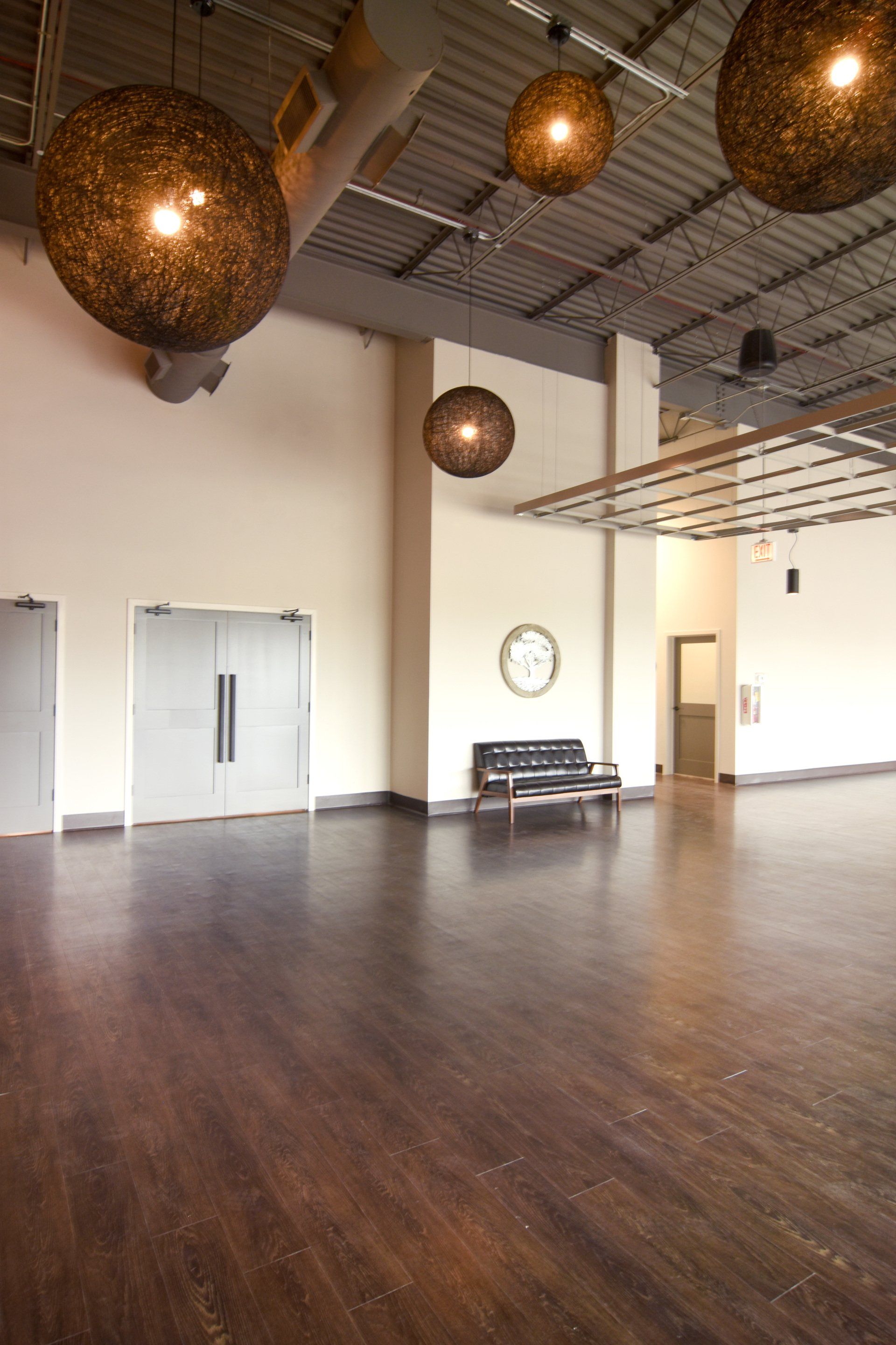 A large empty room with a bench and lamps hanging from the ceiling.
