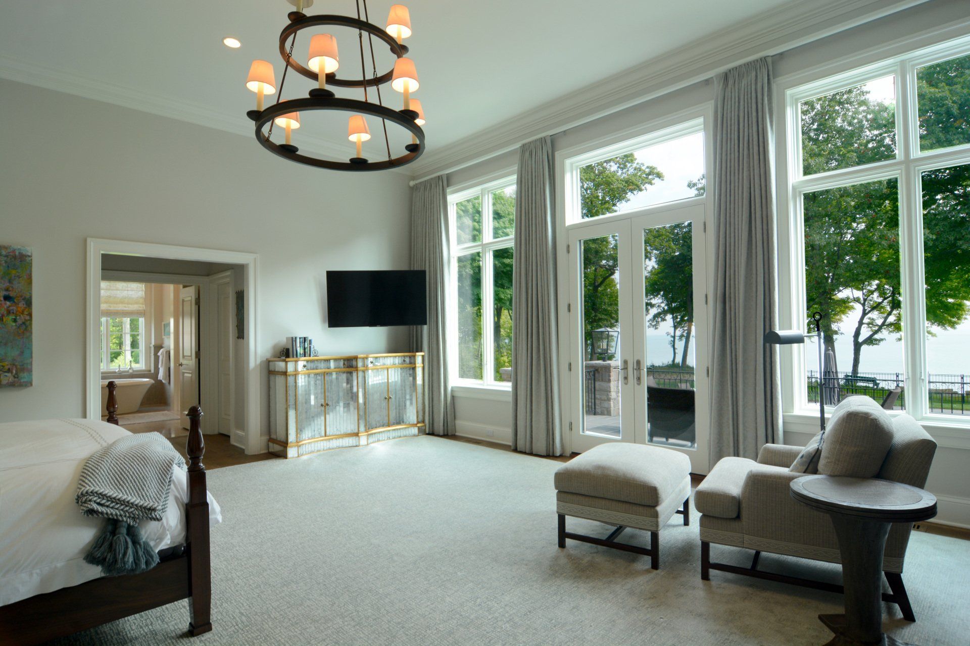 A bedroom with a bed , chairs , ottomans and a television.