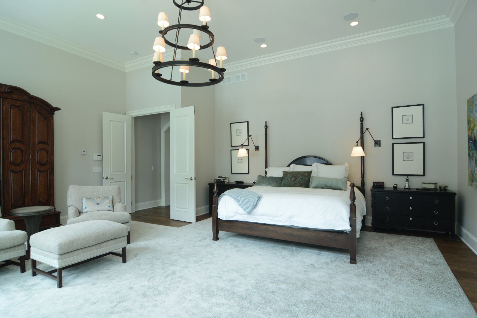 A bedroom with a large bed and a chandelier hanging from the ceiling.
