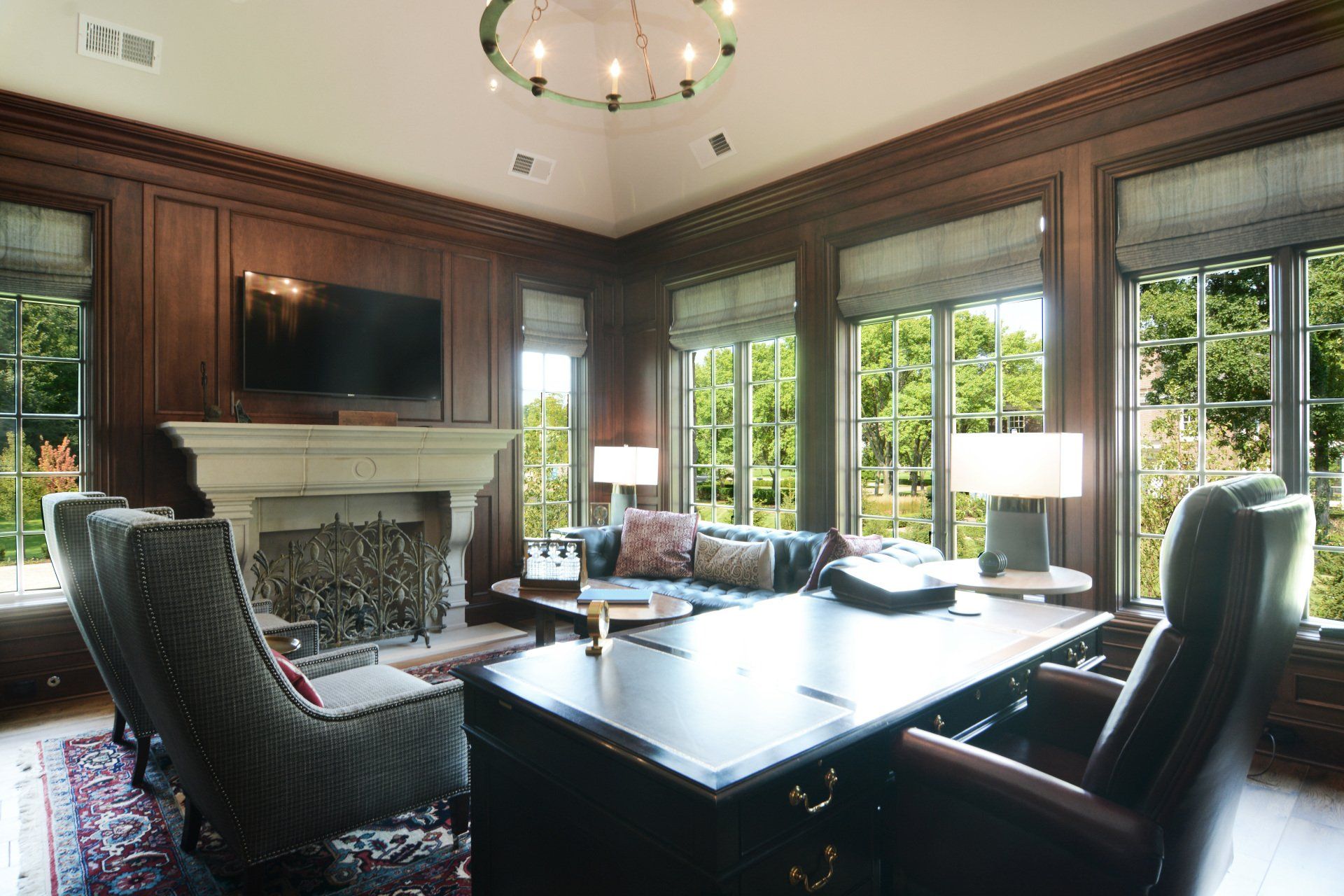 A living room with a desk and chairs and a fireplace