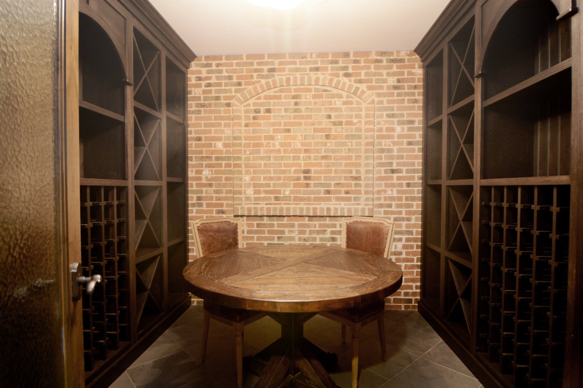 A wine cellar with a table and chairs and a brick wall.