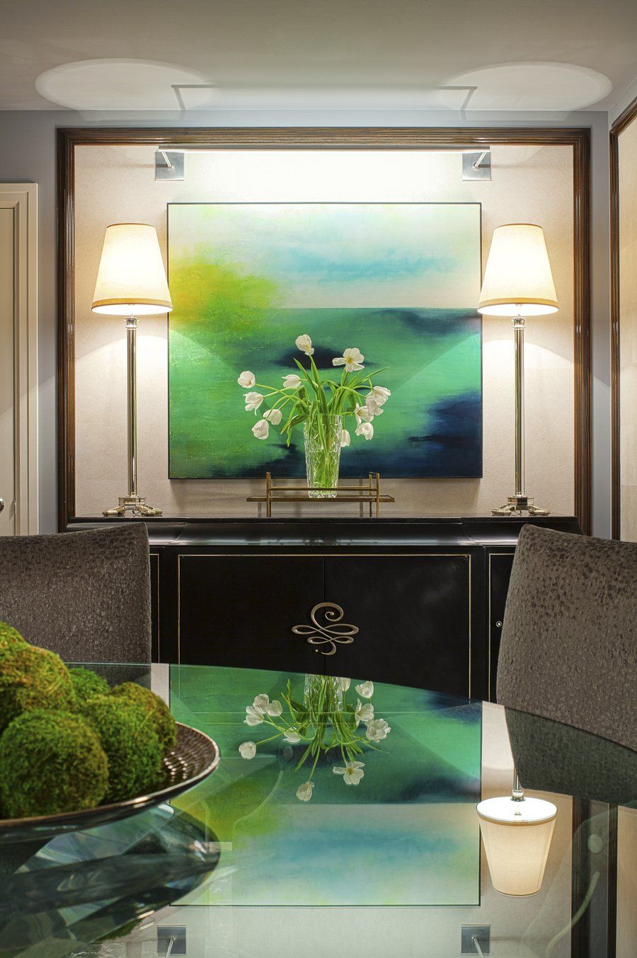 A dining room with a painting on the wall above the table