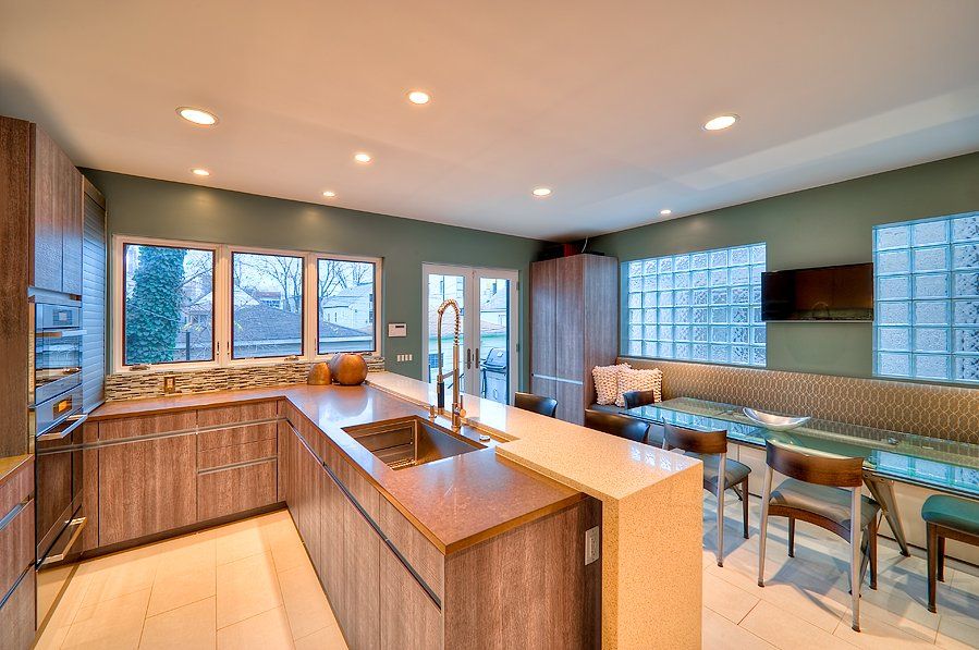 A kitchen with a large island , sink , dining table and chairs.