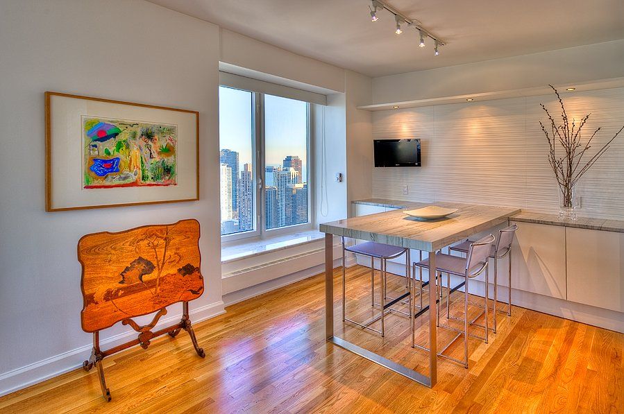 A living room with a table and chairs and a painting on the wall.