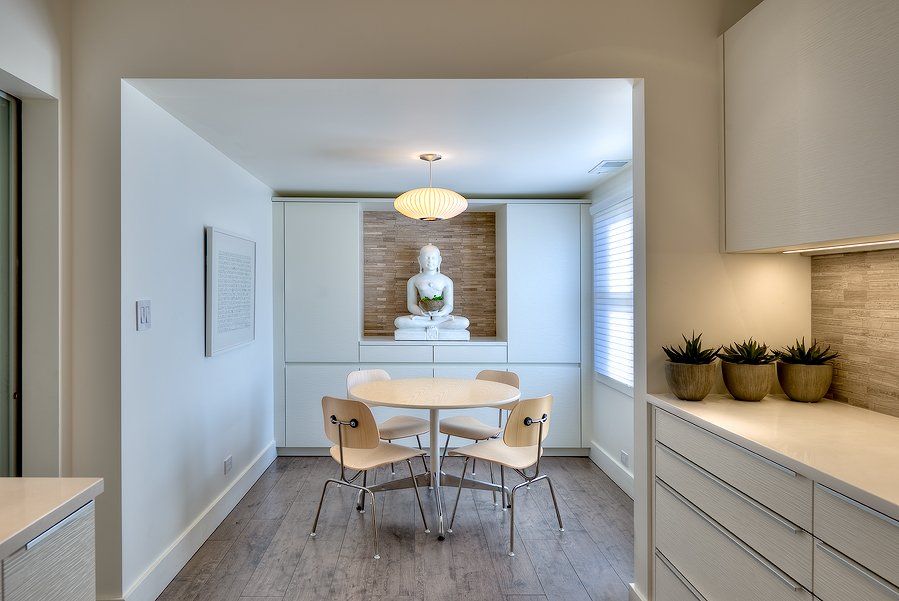 A dining room with a table and chairs and a statue on the wall.