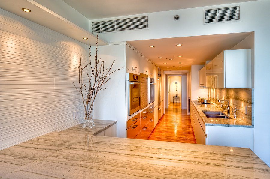 A kitchen with white cabinets and a marble counter top