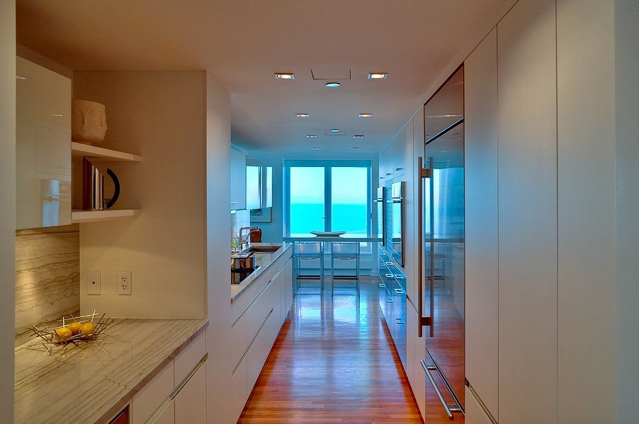 A long hallway leading to a kitchen with a view of the ocean