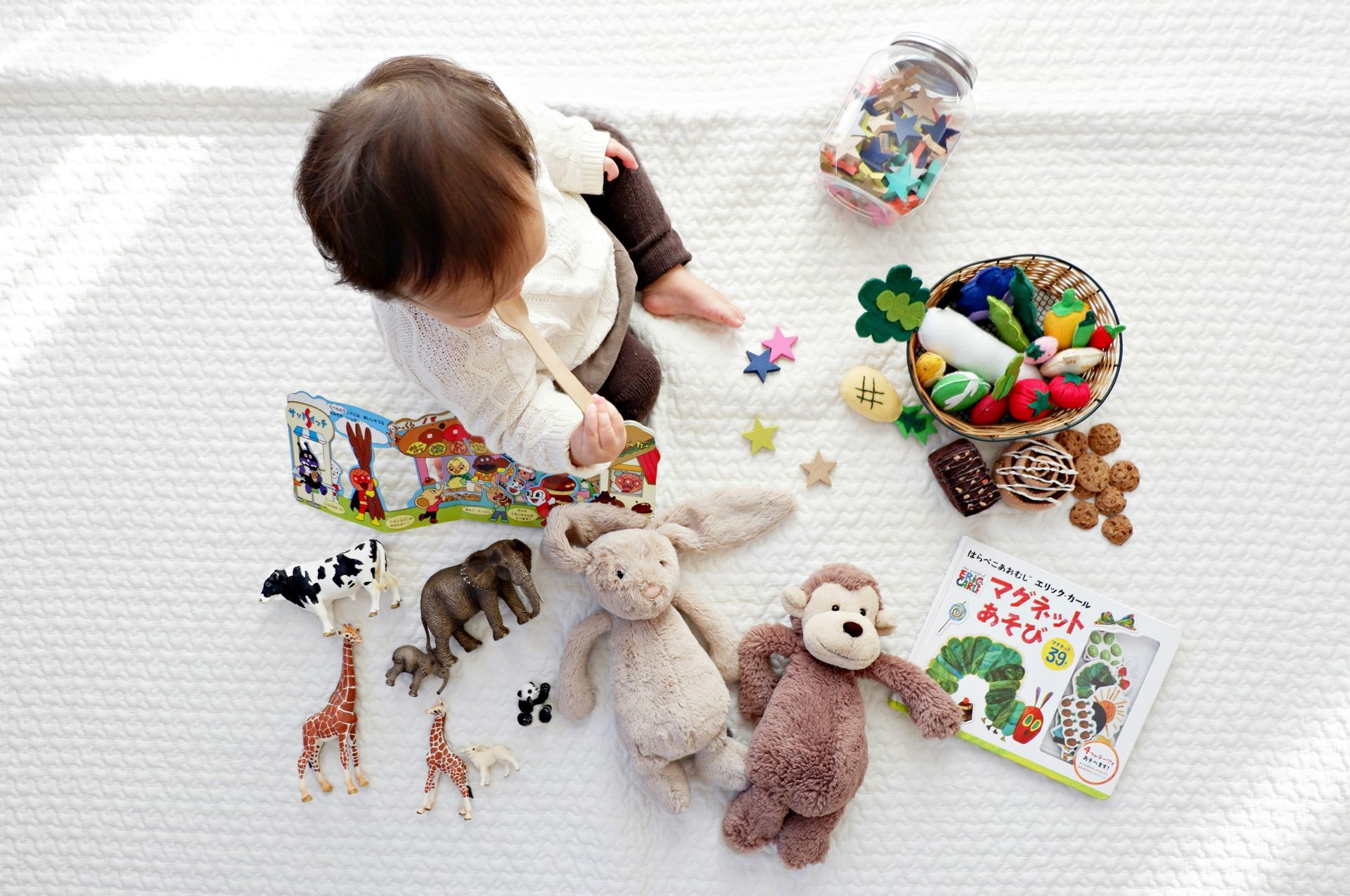 A baby is sitting on the floor playing with toys and a book.