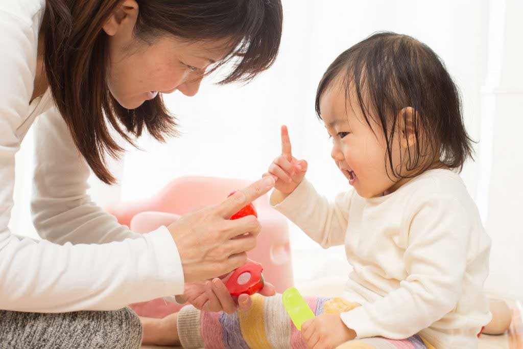 A woman is playing with a baby on the floor.