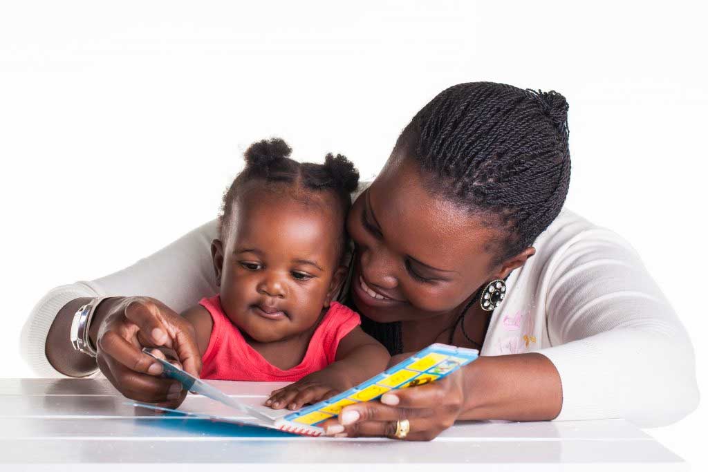 A woman is reading a book to a little girl.