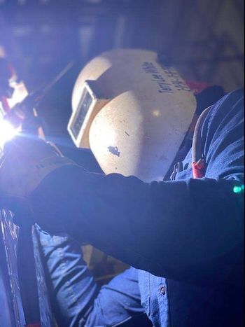 A man is welding a piece of metal in a garage.