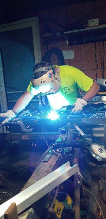 A man is welding a piece of metal in a factory.