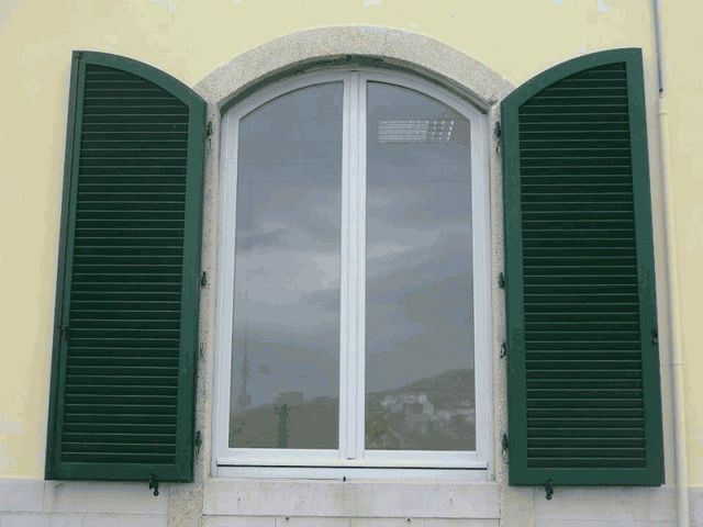 finestra bianca ad arco con persiana verde aperta