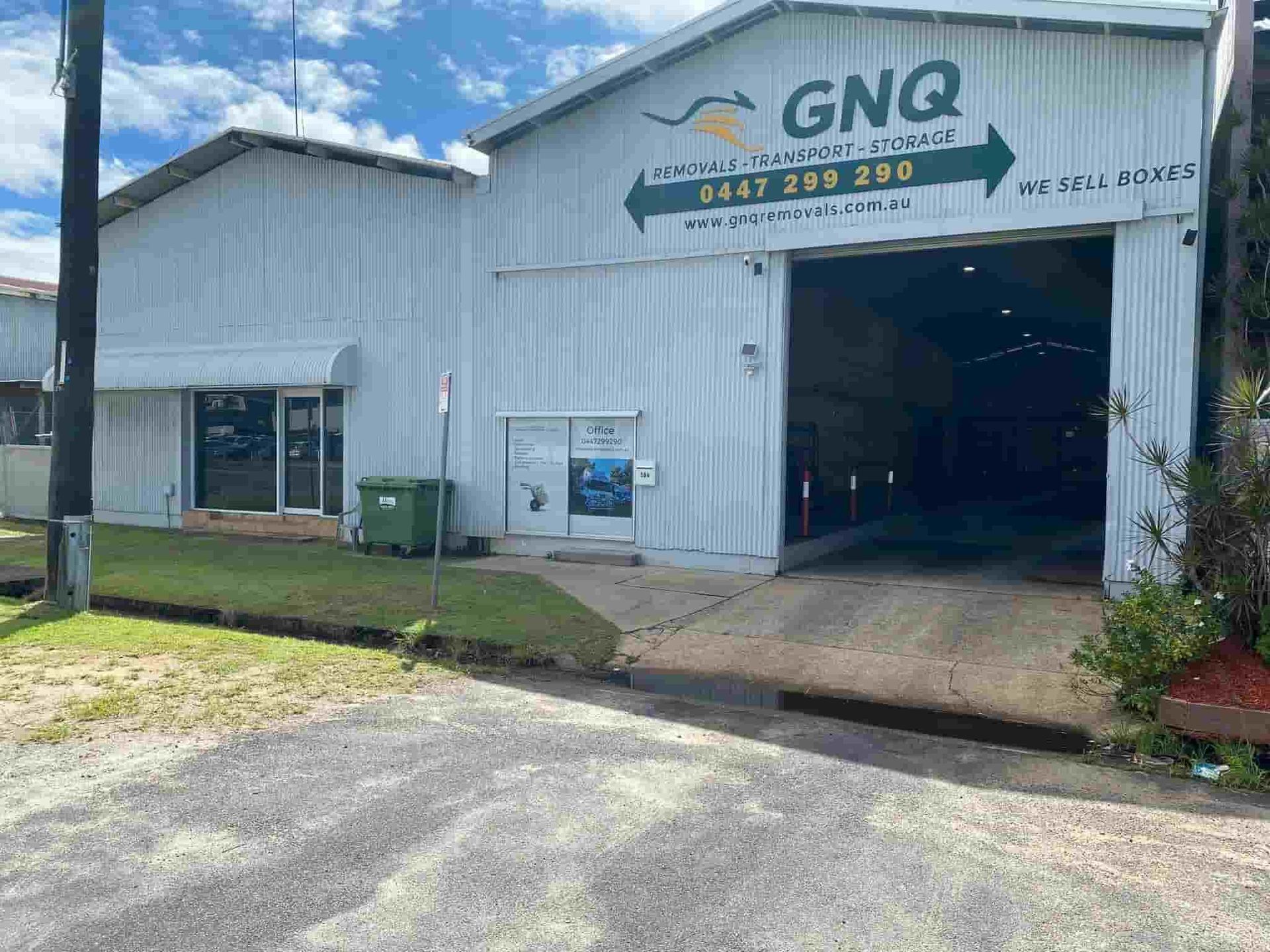A Large White Building With a Green Arrow Pointing to the Right — GNQ Removals–Transport–Storage In Portsmith, QLD
