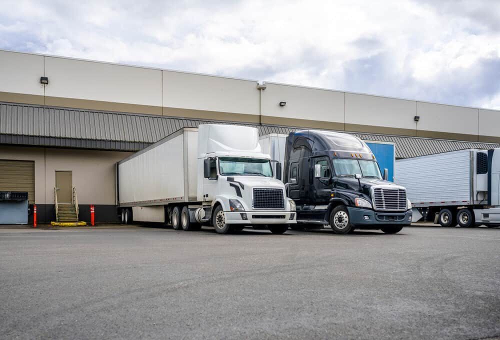 Three Semi Trucks Are Parked in Front of a Warehouse — GNQ Removals–Transport–Storage In Portsmith, QLD