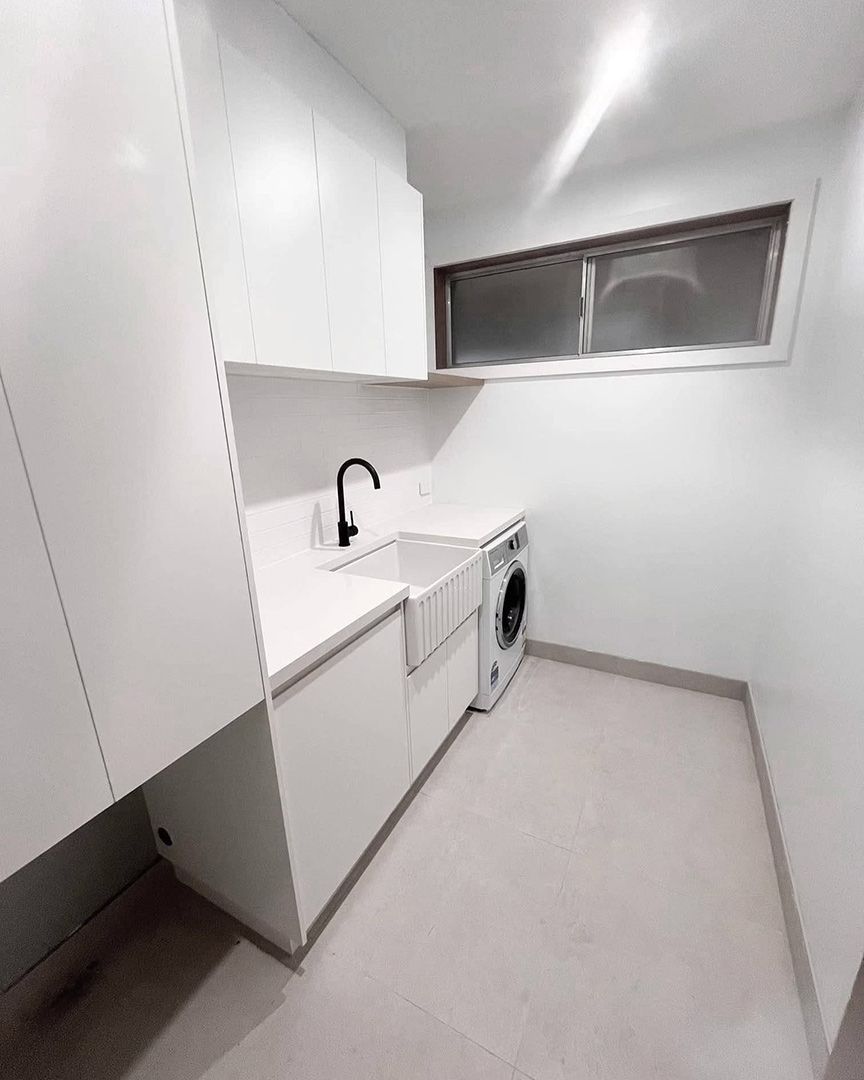 A Laundry Room with White Cabinets , a Sink , a Washer and Dryer , and A Window — VG Cabinets In Warrnambool, VIC
