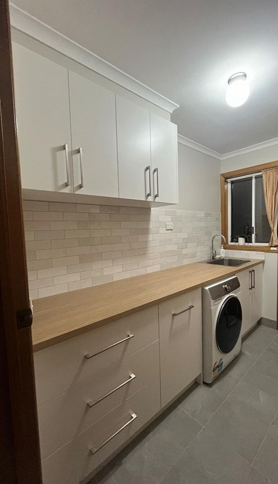 A Laundry Room with White Cabinets , a Washer and Dryer , a Sink , and A Window — VG Cabinets In Warrnambool, VIC