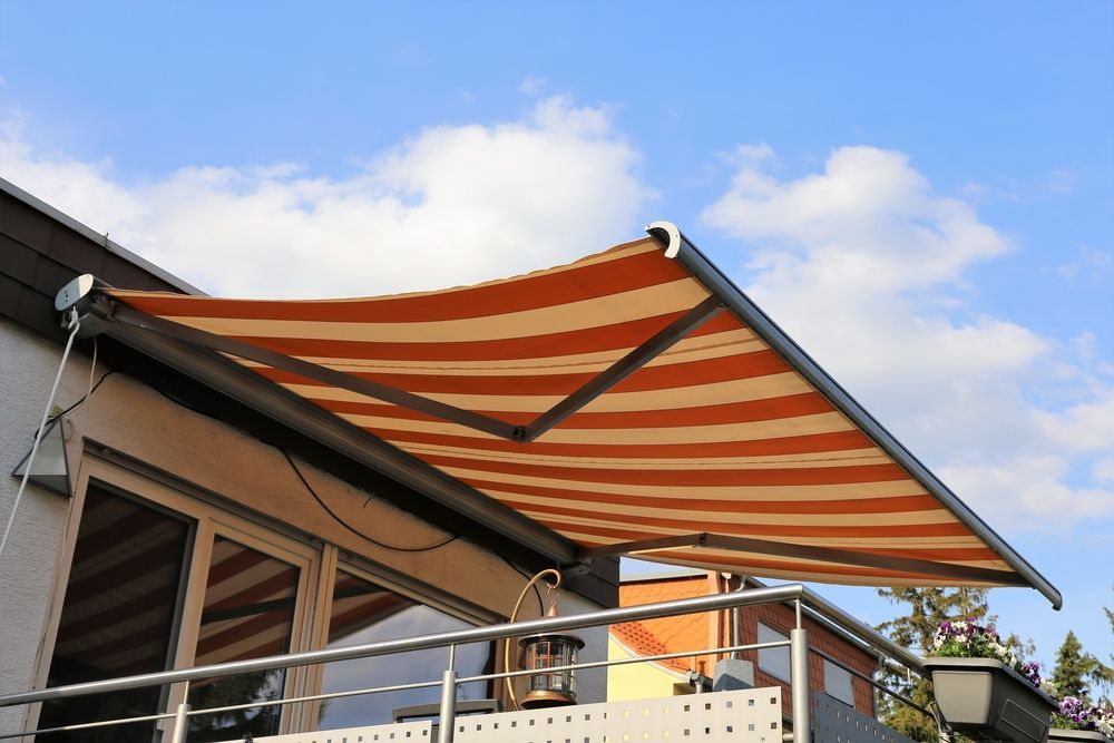 Striped Retractable Awning Extended Over a Balcony on a Building — Wares Blinds, Screens & Awnings In Mount Larcom, QLD