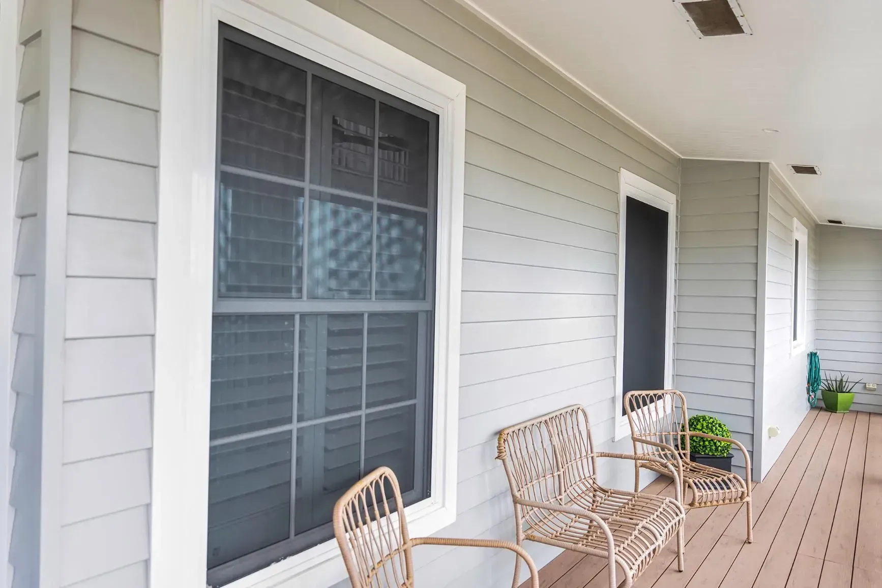 View of A Porch with Windows, Gray Siding, Wicker Chairs, and A Wooden Deck — Wares Blinds, Screens & Awnings In Gladstone Central, QLD