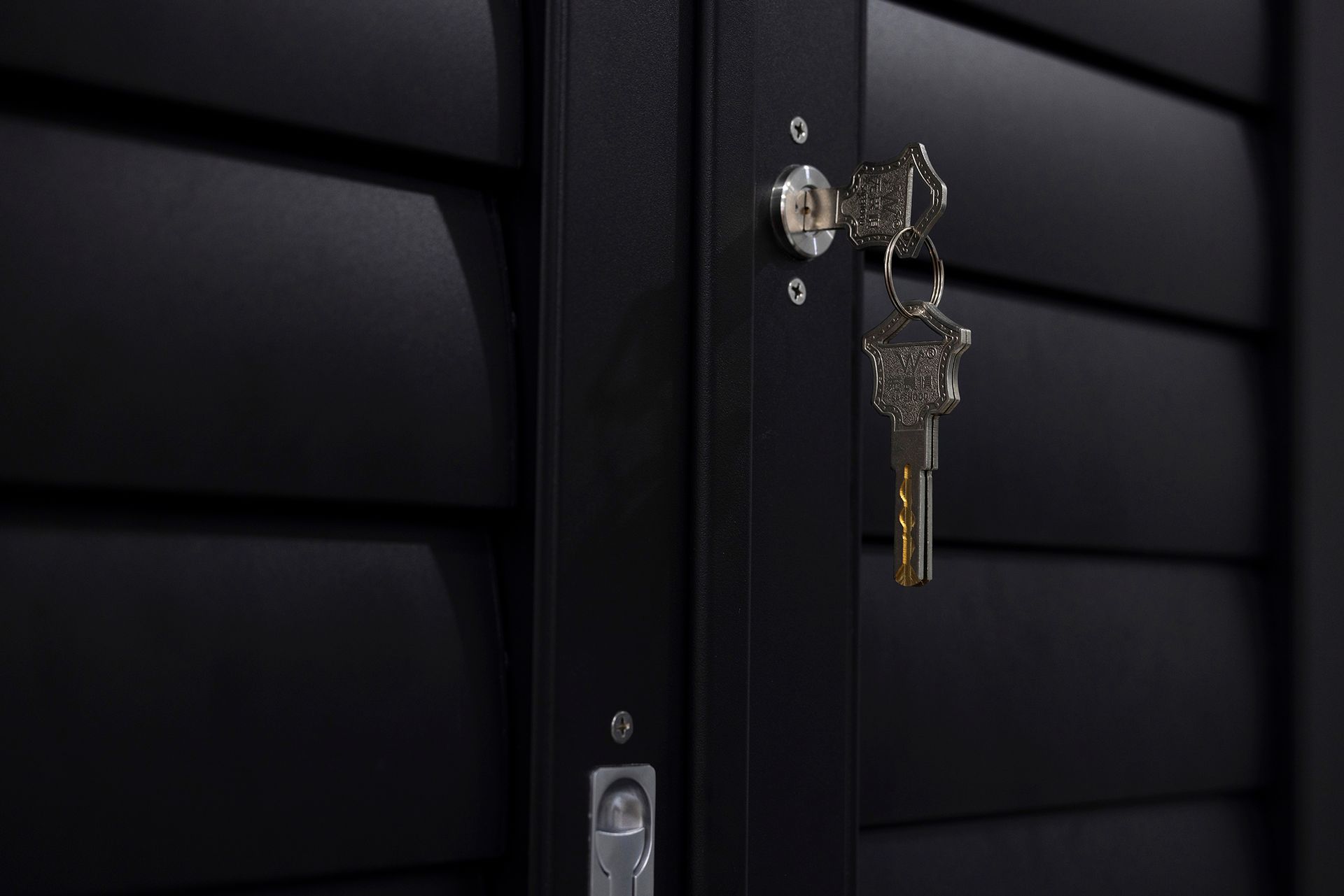 Black metal gate with keys in the lock.