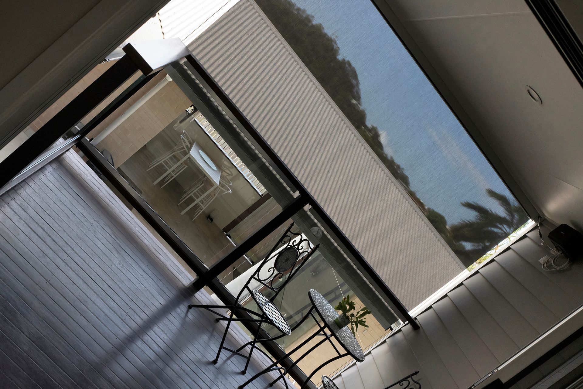 Interior View of A Modern Patio with Black Framed Glass Doors, Leading to An Outdoor Patio with White Furniture — Wares Blinds, Screens & Awnings In Gracemere, QLD