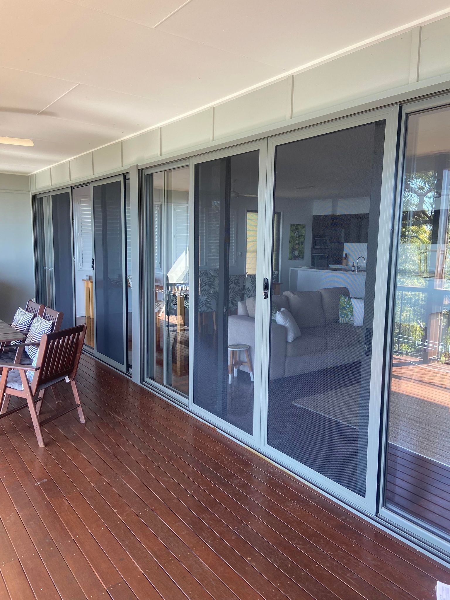 Wooden deck with multiple sliding glass doors and screens, leading into a living area.