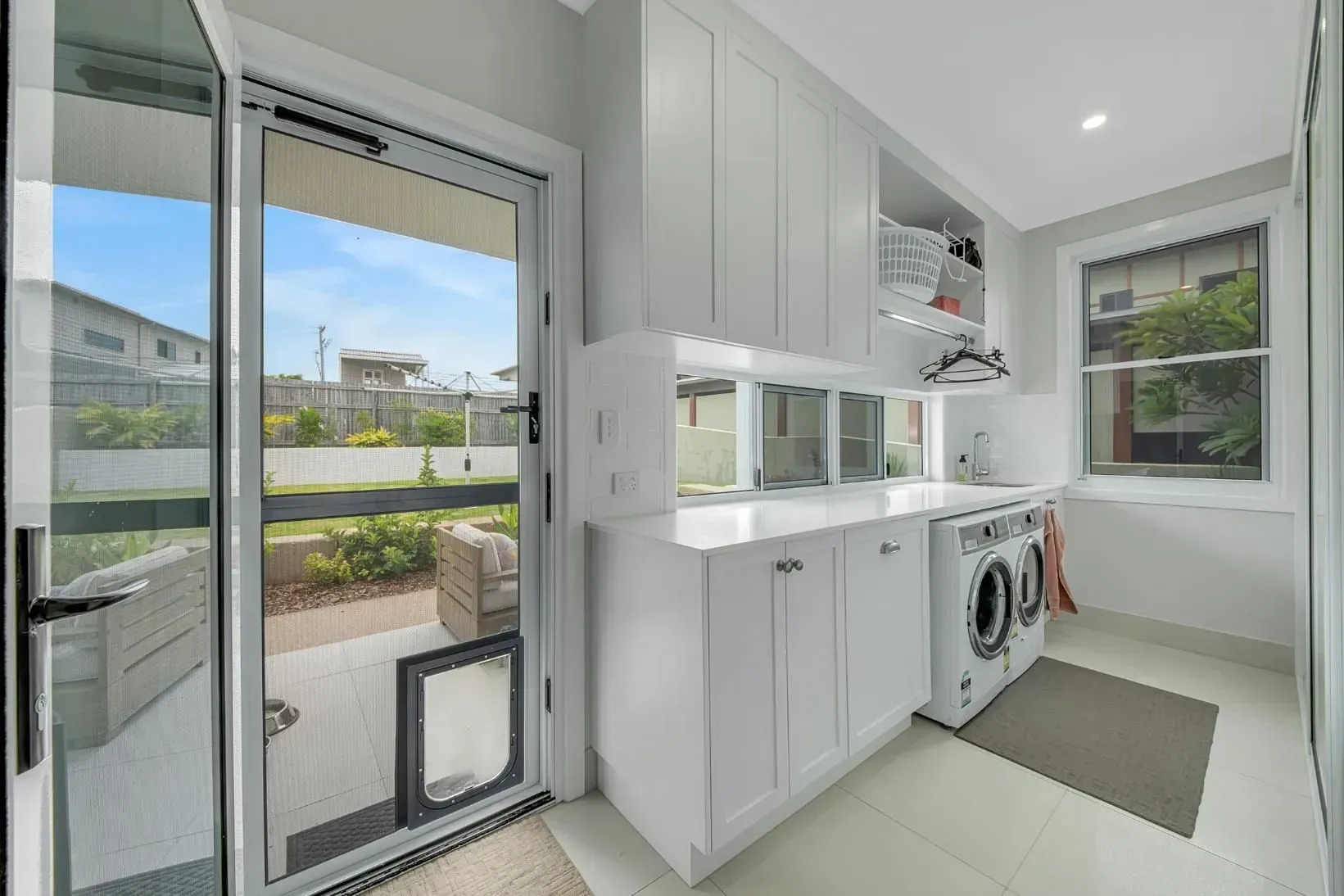 Laundry Room with White Cabinets, Washing Machine, and Door to Backyard — Wares Blinds, Screens & Awnings In Gladstone Central, QLD