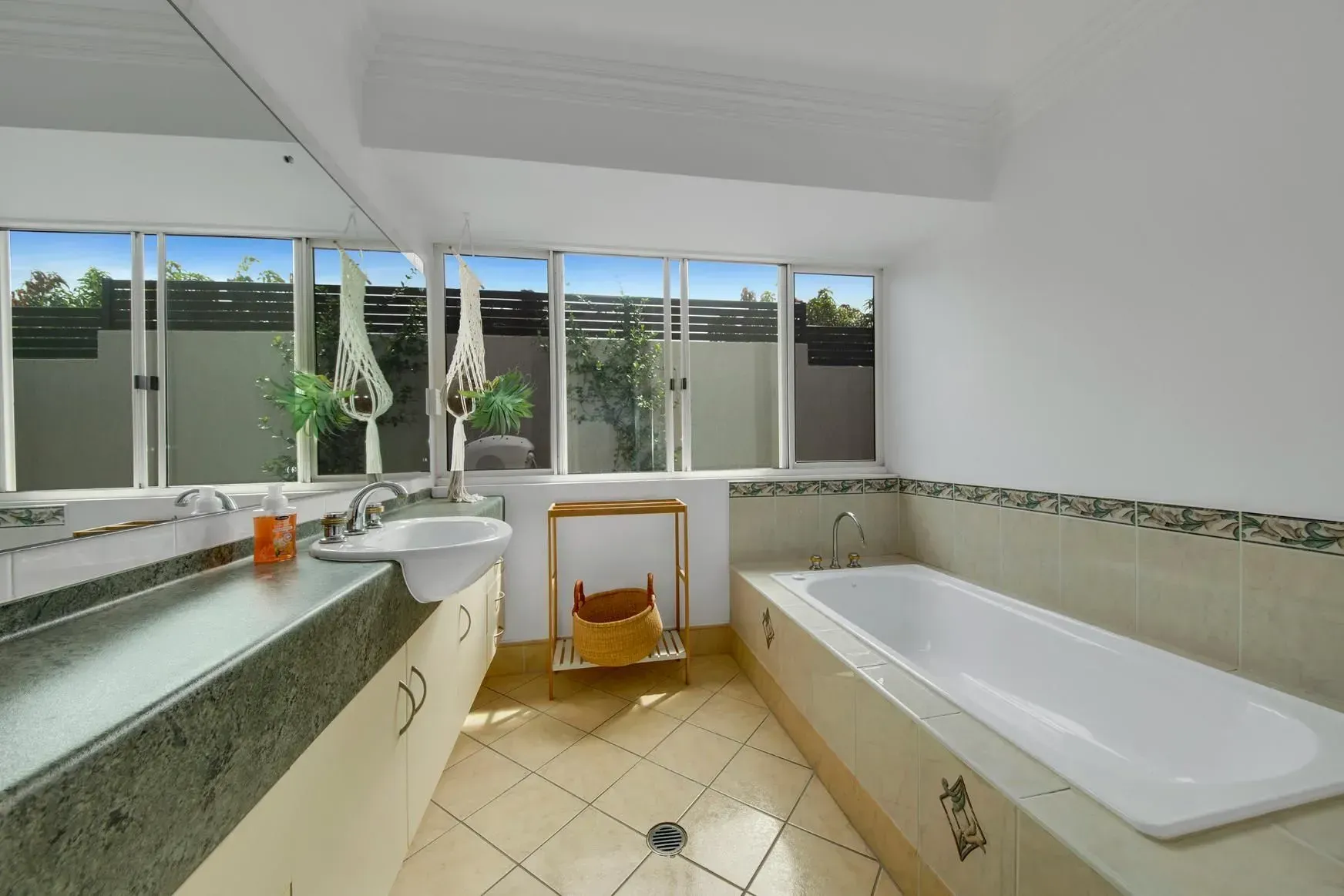 Bathroom with A Long White Tub, Vanity, and A Window Overlooking a Courtyard — Wares Blinds, Screens & Awnings In Gladstone Central, QLD