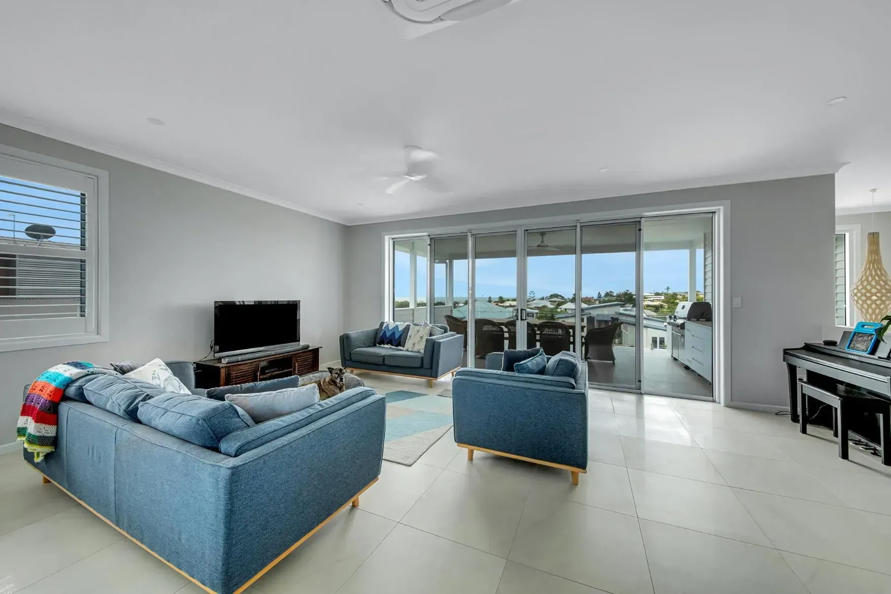 Living Room with Blue Furniture, Large Glass Doors, and A View of The Outdoors — Wares Blinds, Screens & Awnings In Gladstone Central, QLD
