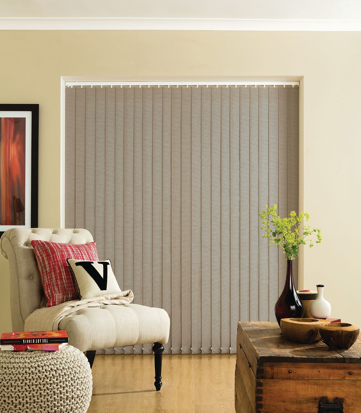 Living room with beige vertical blinds, armchair with pillows, and wooden trunk.