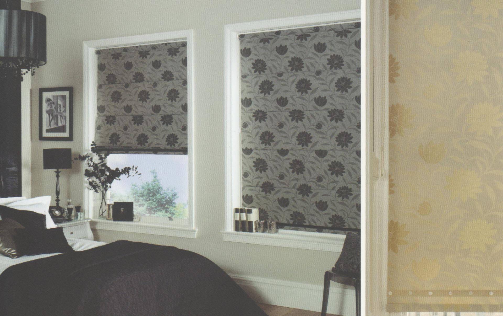Bedroom with dark floral patterned window blinds and a bed.