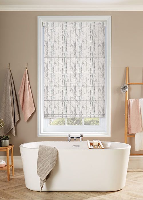 Bathroom scene with a bathtub, window with patterned shade, and towels hanging.
