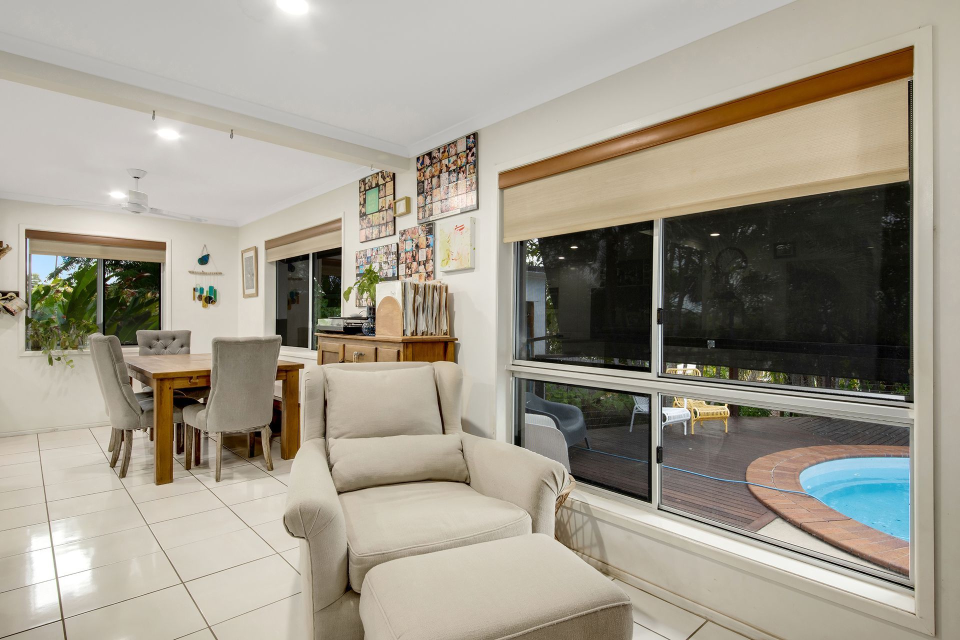 Living room with pool view: beige chair and ottoman, dining table, and large windows Wares Blinds, Screens & Awnings In Gladstone Central, QLD