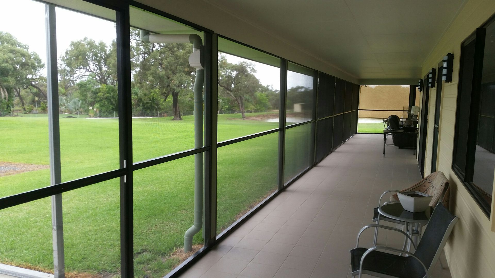 White double doors with screen, flanked by potted plants, on brick porch.