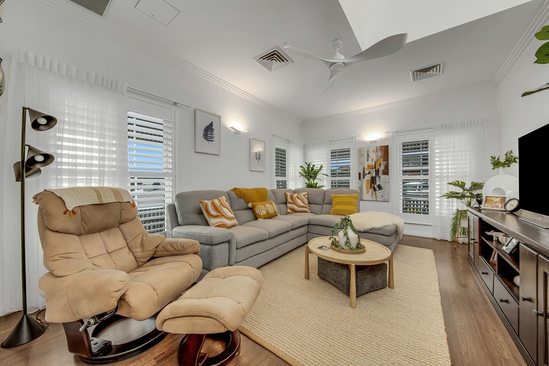 Living room with gray sectional, beige recliner, coffee table, and large TV.