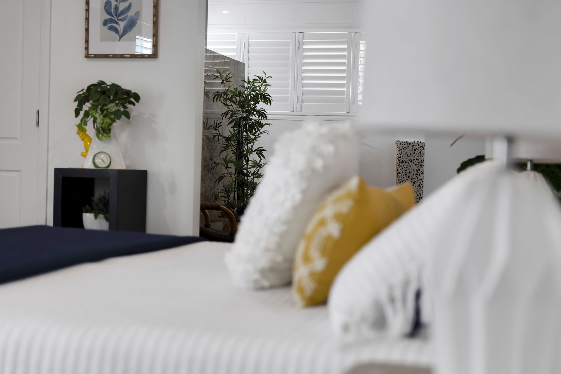 Bedroom With Bed, Pillows, Lamp, and Partial View of a Window With Shutters — Wares Blinds, Screens & Awnings In Gladstone Central, QLD