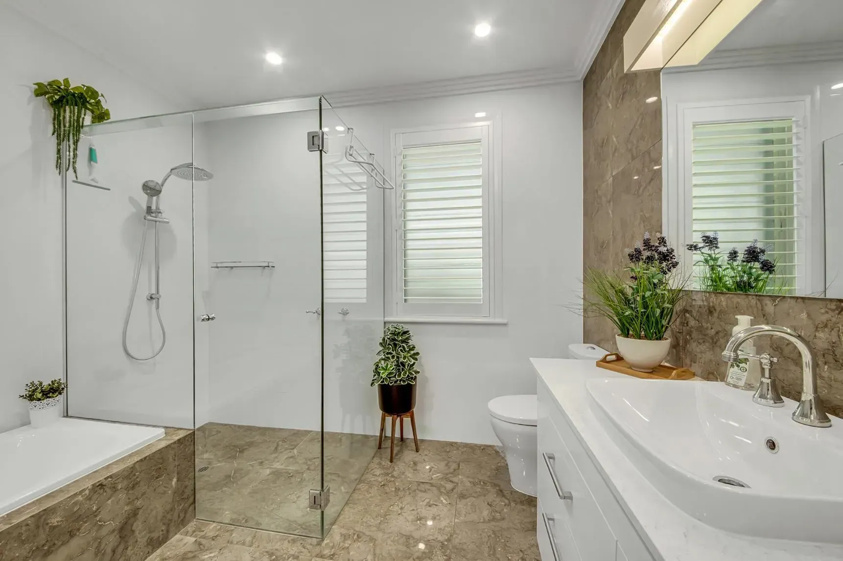 Modern Bathroom with Glass Shower, White Vanity, and Shuttered Window — Wares Blinds, Screens & Awnings In Gladstone Central, QLD