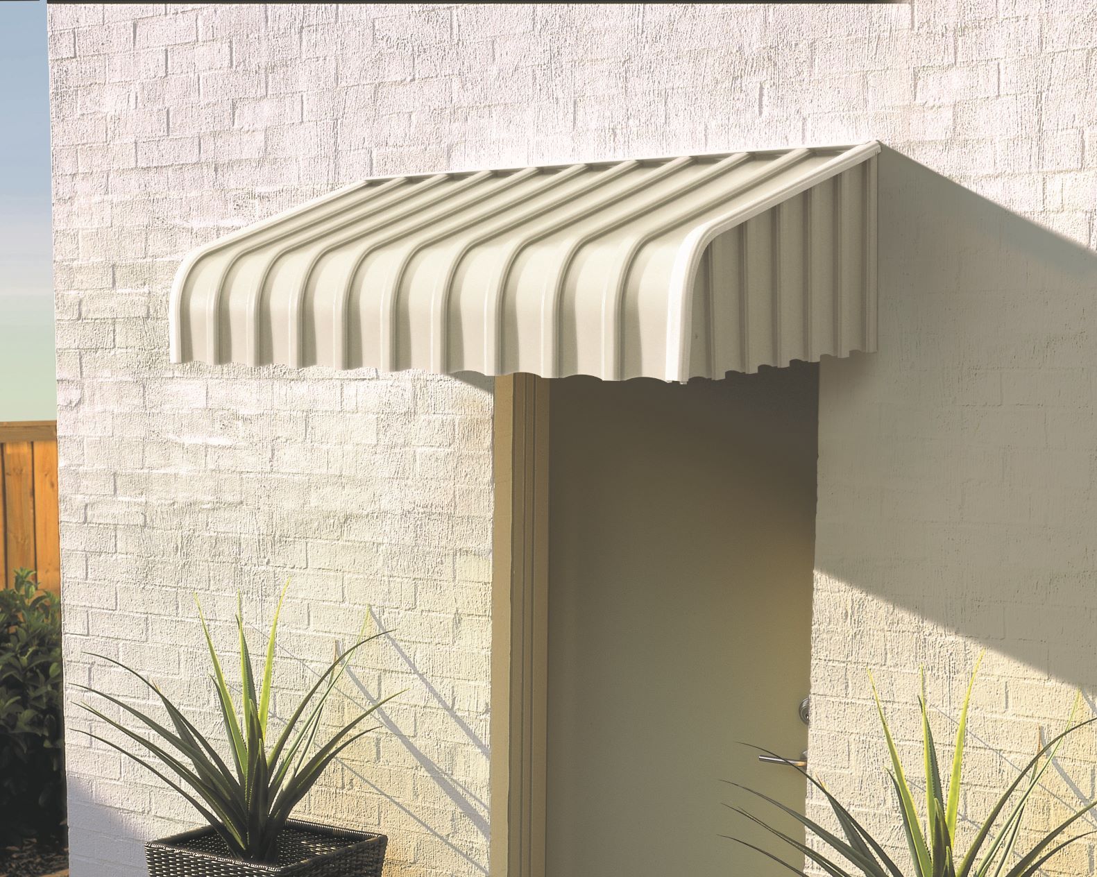 Beige, curved awning over a beige door on a textured, light-colored wall. Two potted plants sit below Wares Blinds, Screens & Awnings In Gladstone Central, QLD