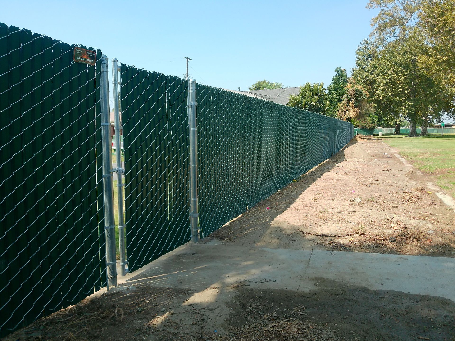 A chain link fence along a dirt path in a park
